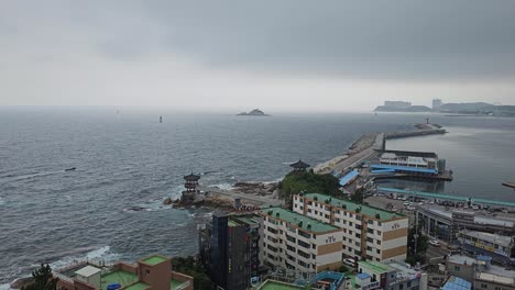 Meereswelle-Kracht-An-Der-Felsigen-Küste-Mit-Dem-Pavillon-Von-Yeonggeumjeong,-Gesehen-Vom-Sokcho-Leuchtturm-An-Einem-Regnerischen-Tag