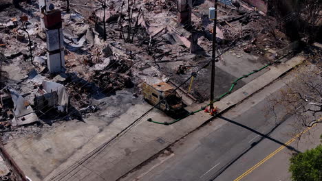 aerial view of an urban area devastated by fire, showing burnt buildings and a charred vehicle