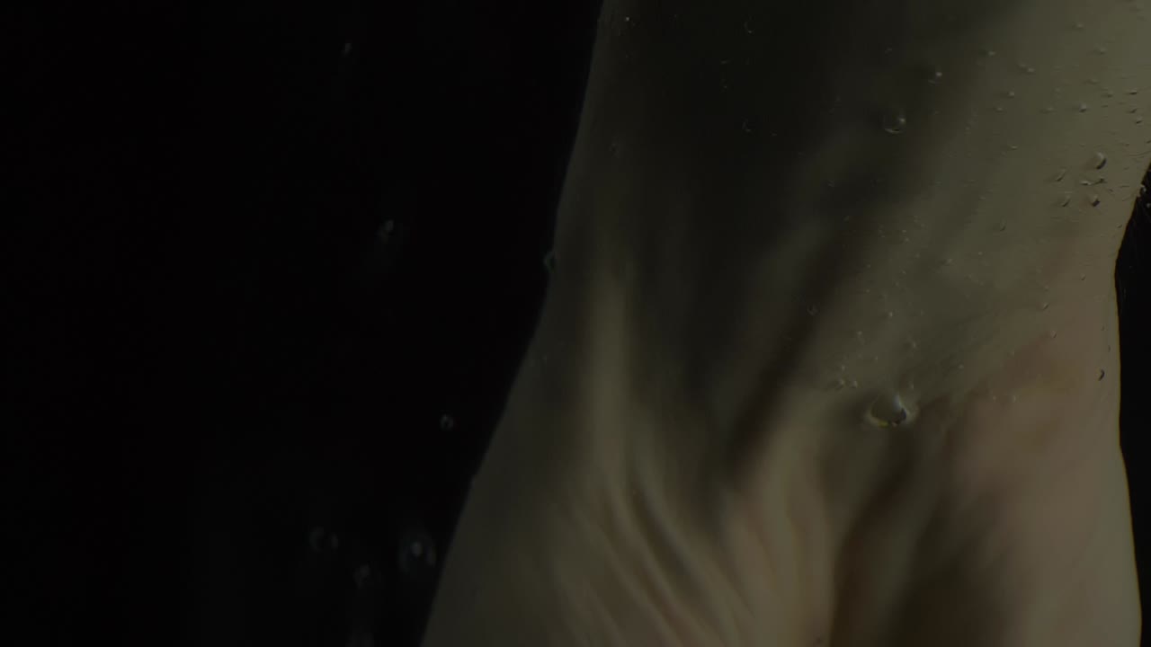 검은색 배경으로 물에 녹색 사과가 있는 내림차순 손을 닫습니다.