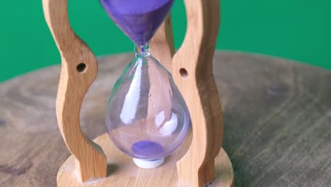 hypnotic one minute running vintage hourglass on wooden table and green screen.