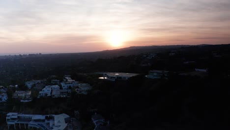 Toma-Aérea-Inversa-Alta-Y-Ancha-De-La-Ciudad-Del-Siglo-Y-Las-Colinas-De-Beverly-Durante-La-Puesta-De-Sol