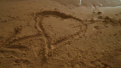 Heart-sand.-Heart-drawing-on-sand-beach.-Panning-from-heart-sign-on-sand-to-sky