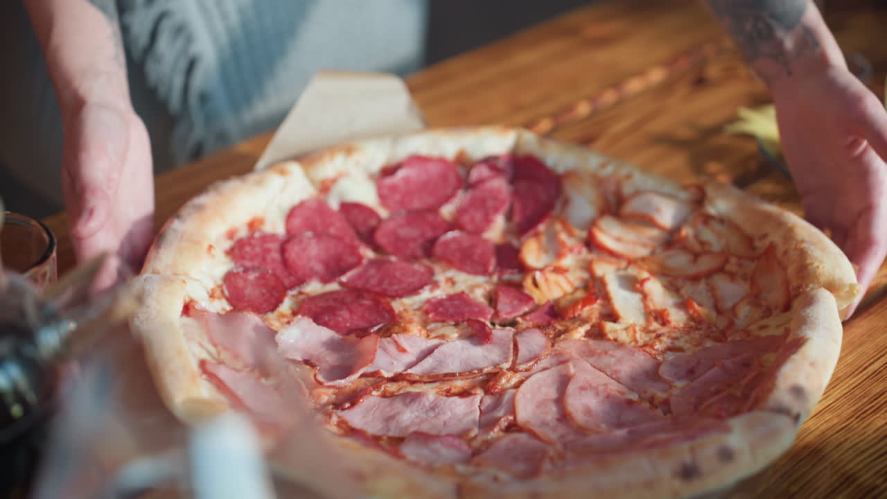 Young woman happily carrying grilled chicken pizza from the table, smiling, enjoying time with friends, cozy indoor setting with wooden walls, capturing a moment of happiness and sharing food
