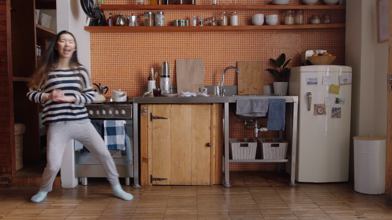 행복한 춤추는 여성 주방에서 달  ⁇ 기 성공적인 라이프 스타일을 축하 즐거운 승리의 춤 축하 주말에 집에서