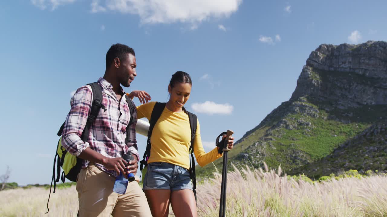 pareja afroamericana caminando mientras trekking en las montañas