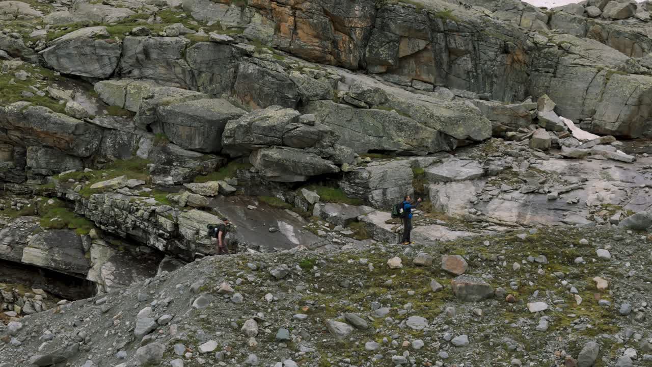 Valmalenco, Italy - Trekkers Navigating the Rugged Landscape of the Fellaria Glacier - Aerial Pullback Shot