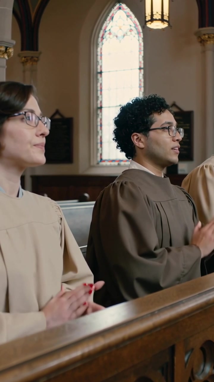 Vertical video: Clapping after hymn start, choir duo in robes singing at church pew, stained-glass