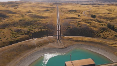 long pipelines directing flowing water into hydroelectric power station on lakeshore