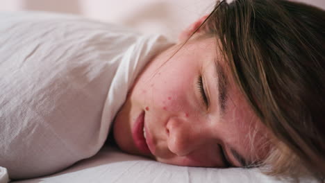 client face tightly pressed against soft surface with eyes squeezed shut during intense face massage, displaying raw expression of pressure and sensation, wrapped in white sheet, shot in indoor spa