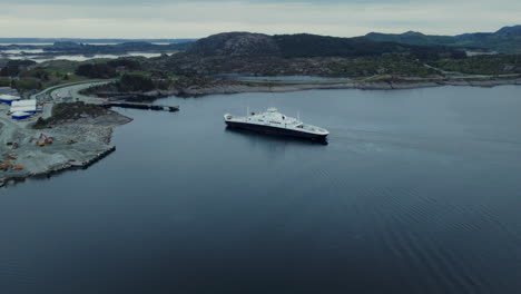 aerial orbiting shot of a ferry arriving to dock at a port in norway