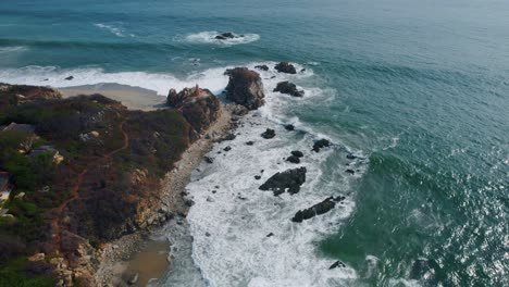 Vista-Aérea-Aérea-De-Las-Olas-Rompiendo-Contra-La-Costa-Rocosa-De-Punta-Zicatela