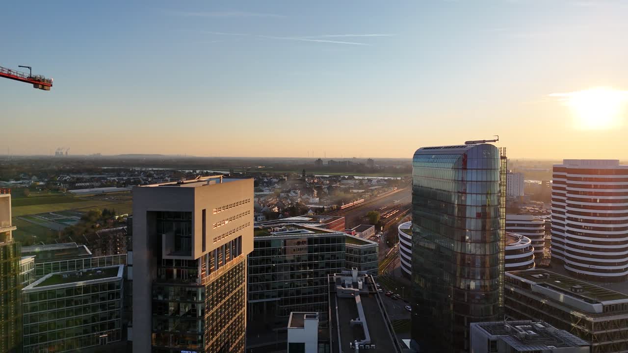 Drone avança entre torres de escritórios altas em direção ao pôr do sol com movimento de trem e brilho de lente.