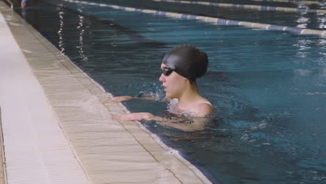 a young female swimmer athletically exits the pool after a swimming session