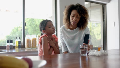 worried biracial mother and sick daughter having smartphone video call with doctor, slow motion