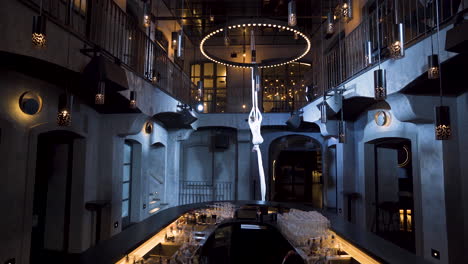 female aerialist spinning while climbing up on silks in a music club