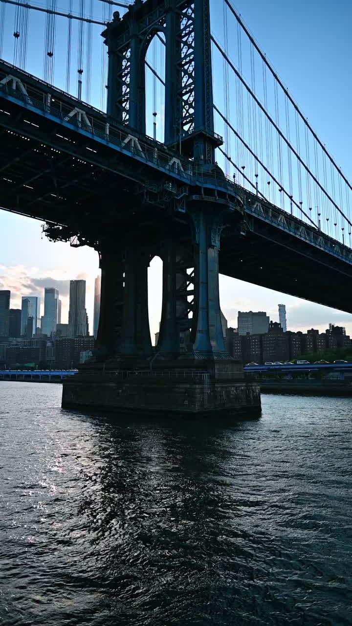 In barca sotto il Manhattan Bridge. Skyline di New York con sole al tramonto tra i grattacieli. Video verticale