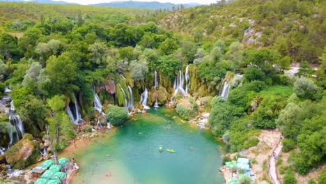 locals and tourists enjoying kravica waterfall with green nature landscape in bosnia and herzegovina