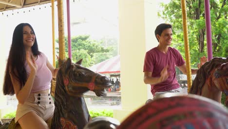 couple in love riding on carousel together at the amusement park outdoors in summer having fun in vacation