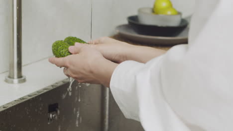 Primer-Plano-De-Manos-De-Mujer-Lavando-Dos-Pepinos-En-Un-Fregadero-De-Cocina-Moderno