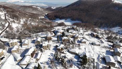 aerial fly above snowed houses, village in mediterranean mountain landscape of nymfaio, florina, greece