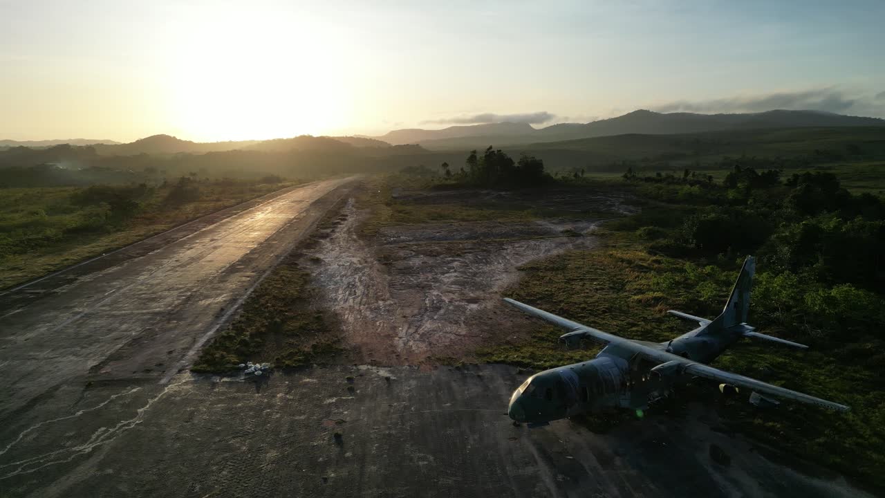 Backwards aerial reveal crashed, abandoned military cargo plane (C-105 Amazonas) at Yanomami´s Surucucu Airport in Roraima, Brazil, during the beginnings of the emergency relief efforts in March 2023