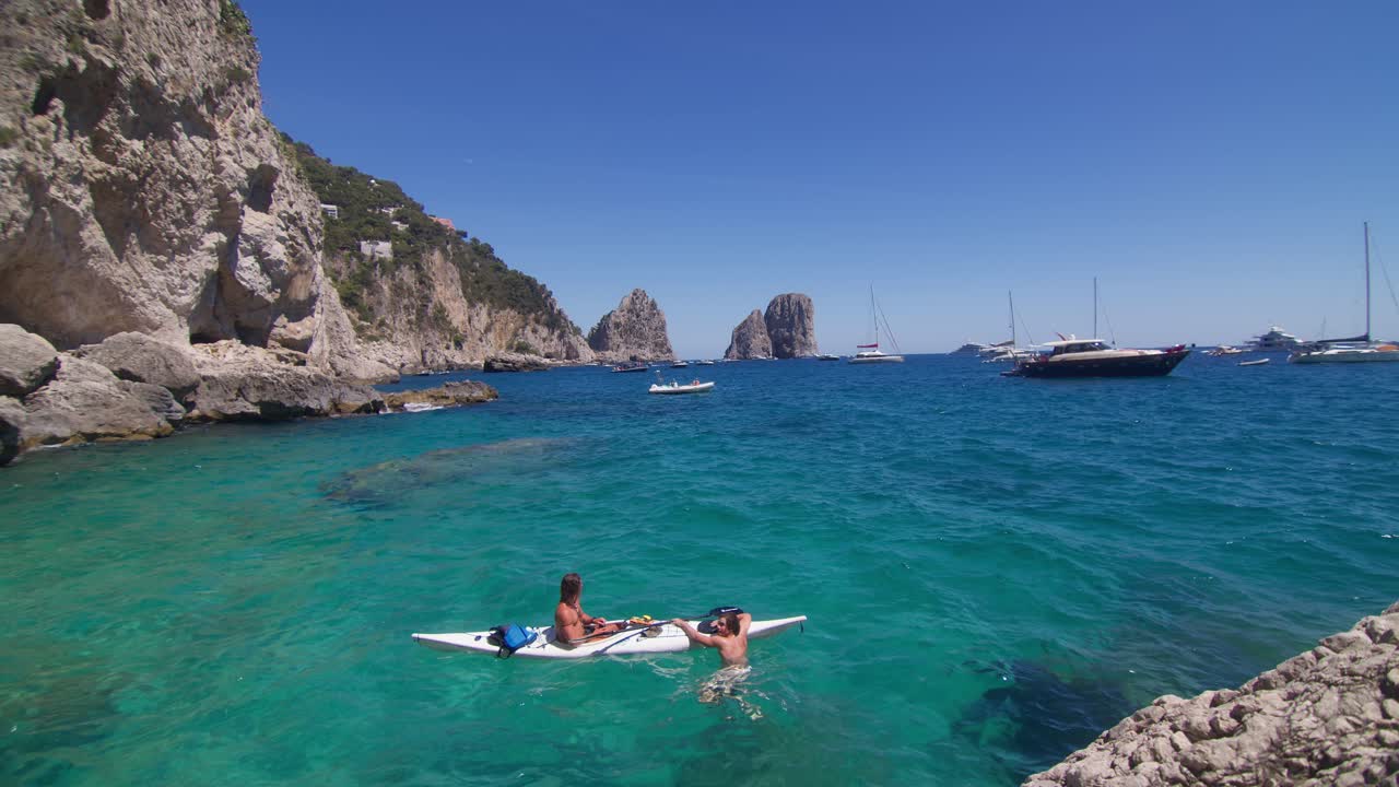 Two friends paddle their kayak in Capri’s crystal waters, enjoying summer sun and friendship