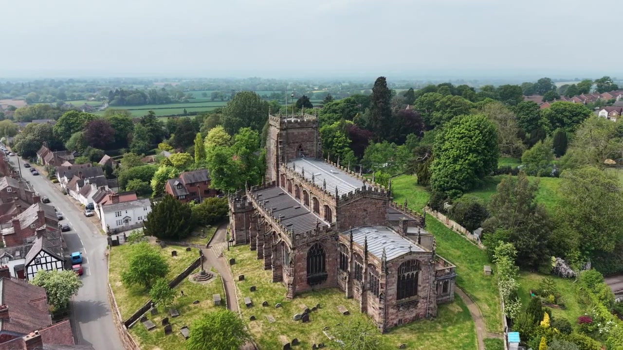 La splendida Chiesa di Sant'Oswald e il circostante villaggio di Malpas - drone in lenta rotazione da dietro, Cheshire, Regno Unito.