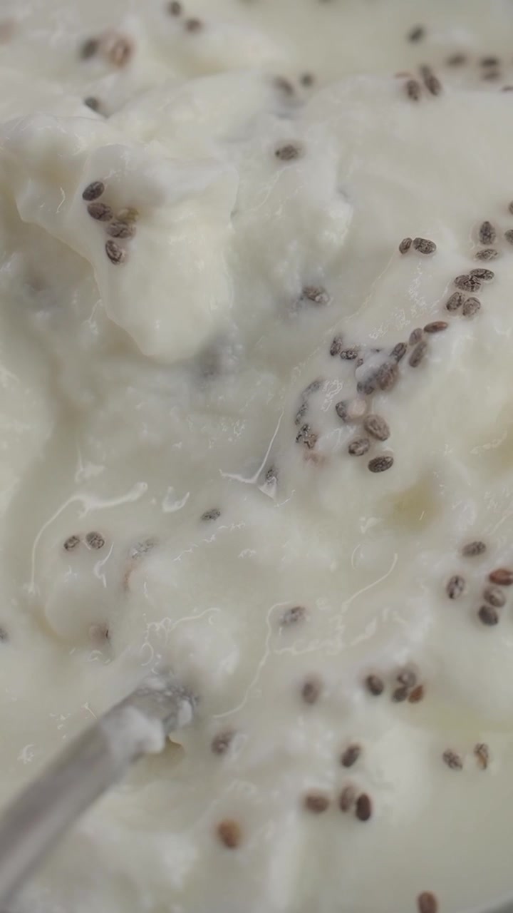 Nærbillede af en ske, der blander chiafrø i cremet yoghurt