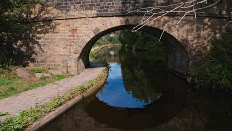 drone footage of a canal with a stone built bridge set in todmorden, halifax, west yorkshire england