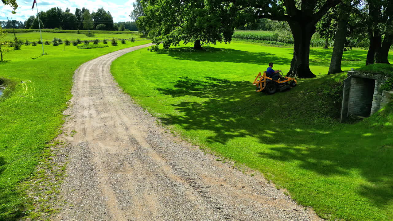 Person Mowing Lawn on a Sunny Summer Day in the Countryside