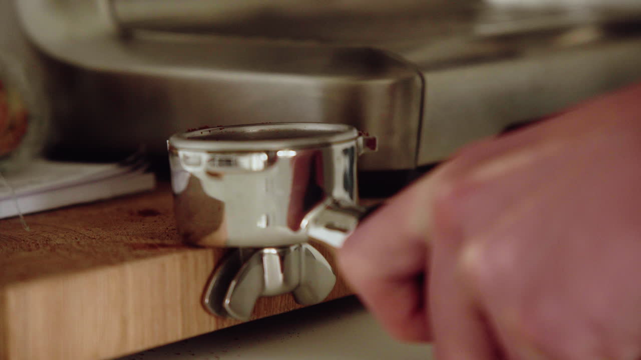 남성 바리스타는 부엌에서 집에서 성질을 내며 그라운드 커피를 탬핑합니다