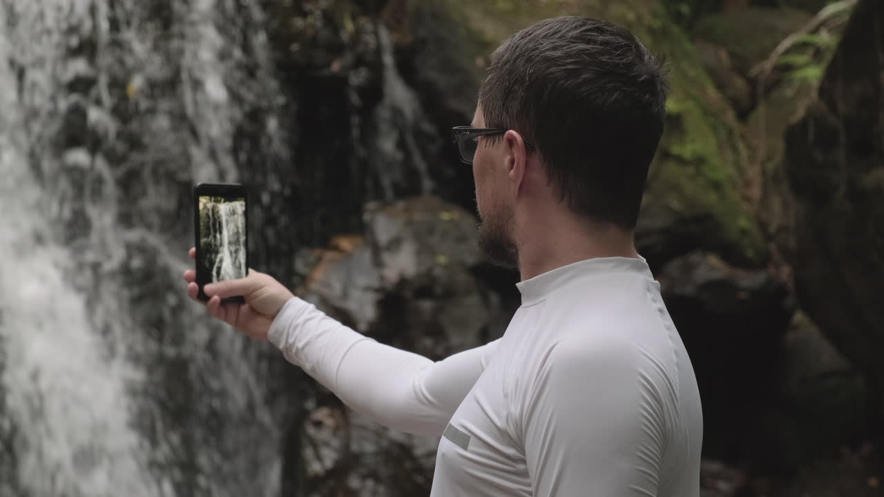 폭포 앞에서 셀피를 찍는 남자