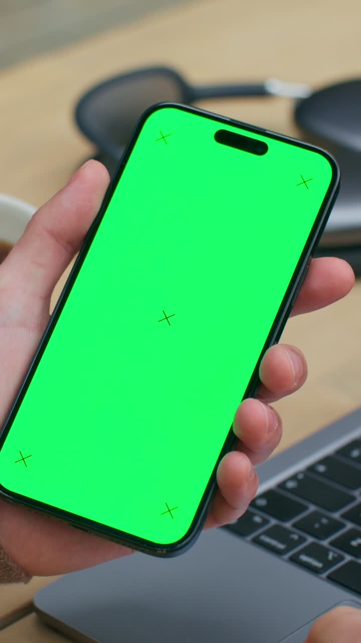 Smartphone con schermo verde su una scrivania