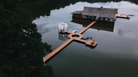 Imágenes-Aéreas,-órbita,-Ascenso,-De-Una-Casa-De-Vacaciones-Sobre-Pilotes-En-El-Agua-Del-Océano.