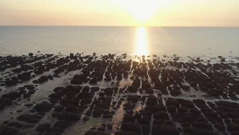 Luftdrohne-Erschossen-Bei-Sonnenuntergang-Zur-Goldenen-Stunde,-Der-über-Sandstrand-Mit-Felsen-über-Ruhigem-Meer-Mit-Kleinen-Wellen-Im-Alten-Hunstanton-North-Norfolk-UK-Ostküste-Absteigt