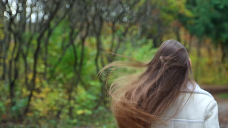 woman with long hair walking through autumn forest