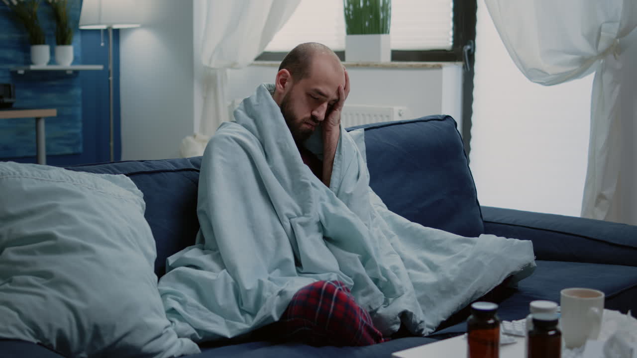 Sick man rubbing temples against headache and cold