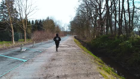 AERIAL-chasing-man-running-through-forest-looking-for-freedom