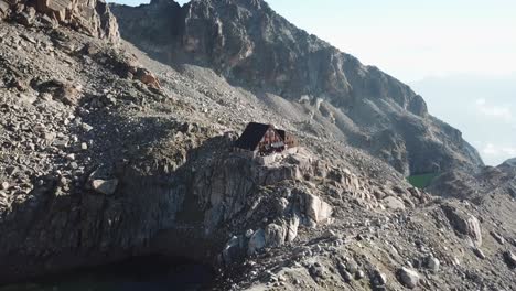 Holzhütte-In-Den-Schweizer-Alpen,-Inmitten-Hoher-Und-Steiler-Felsiger-Berge,-Drohnenrückzug