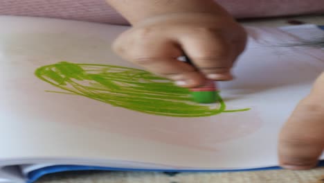 child drawing with green crayon