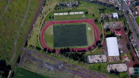 Top-drone-view-of-a-soccer-field-in-the-charming-town-of-chalco-Mexico,-and-view-of-the-highway-town-and-houses-population-density