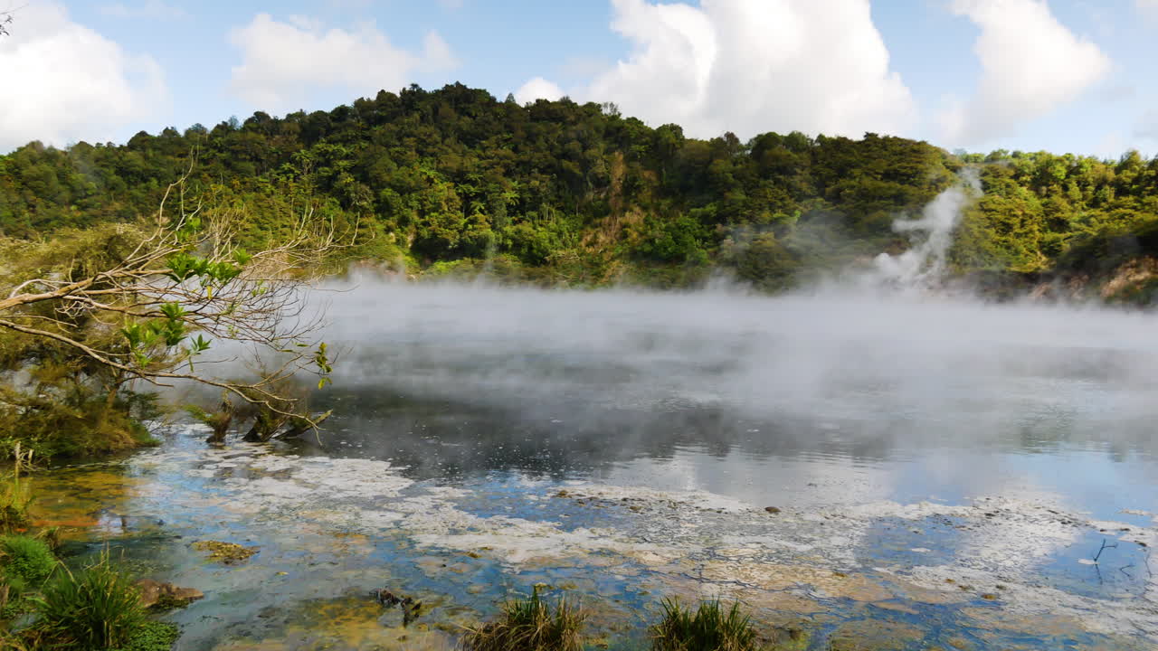 toma panorámica de vapor tóxico volando sobre el lago de la sartén con montañas verdes en el fondo - valle del rift volcánico de waimangu en nueva zelanda - 4k