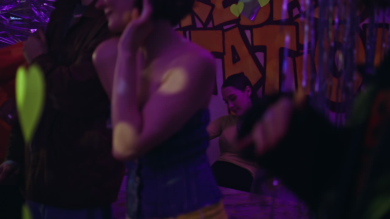 Adam gece kulübünde kadını dansa davet ediyor. Disko kulübünde dans eden genç insanlar grubu.