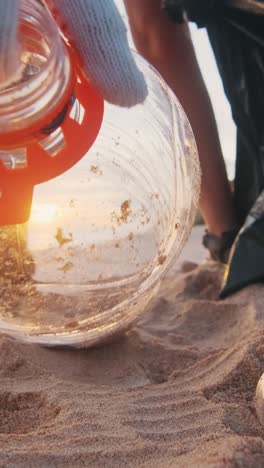 volunteer walks along beach clearing garbage and plastic waste from coast