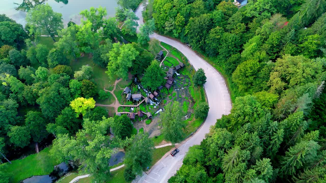 Aerial drone view of the wooden water mills at Mlinčići, near Jajce in Bosnia and Herzegovina lonely road in green pine tree forest