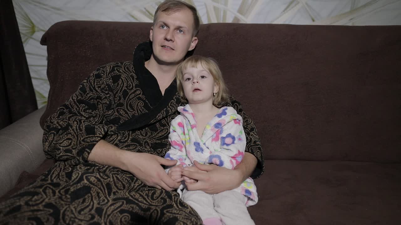 Figlia piccola con suo padre che guardano un film interessante con grande emozione.