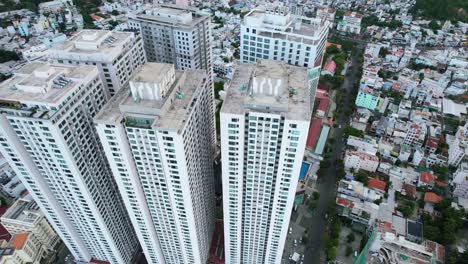 Un-Dron-Aéreo-Que-Rodea-Altos-Y-Antiguos-Edificios-De-Apartamentos-Residenciales-En-La-Ciudad-Asiática-De-Nha-Trang-Vietnam,-Rodeado-De-Barrios-Locales-En-Una-Tarde-Nublada