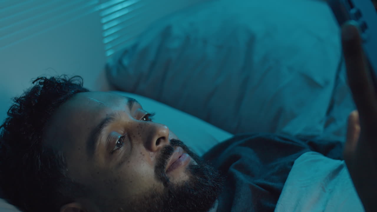 Man Messaging on Phone in Bed at Night