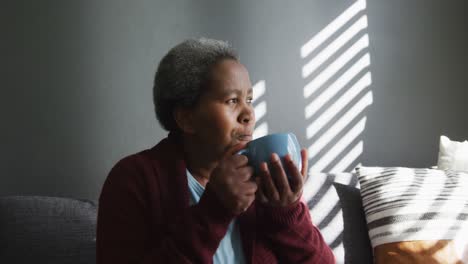 Una-Anciana-Afroamericana-Pensativa-Bebiendo-Café,-Mirando-A-Lo-Lejos