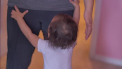 un niño pequeño cuelga de las piernas de su madre mientras ella sostiene a otro bebé en sus brazos